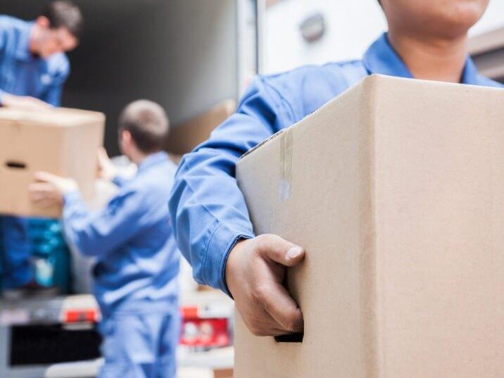 two movers using a dolly to transport a heavy, awkwardly shaped item